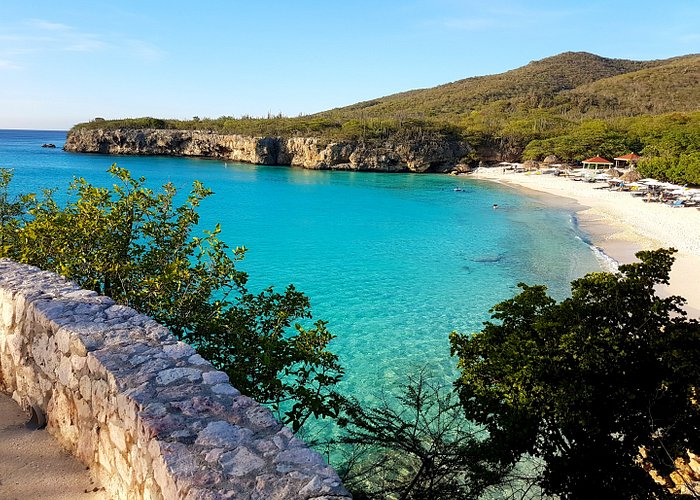praia turquesa com paredao de rocha