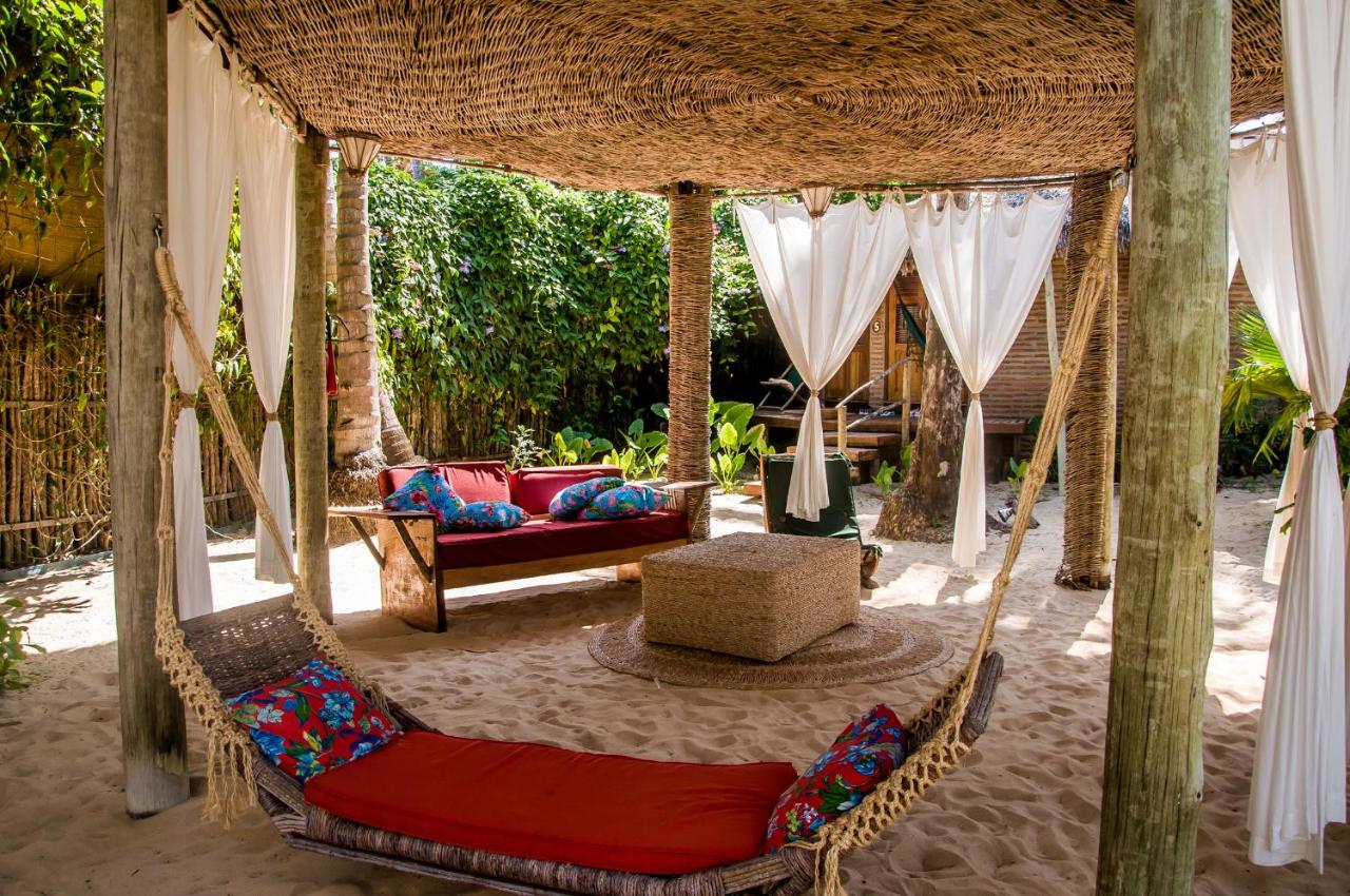 área coberta r´rústica e charmosa com sofás e espreguiçadeiras na areia 